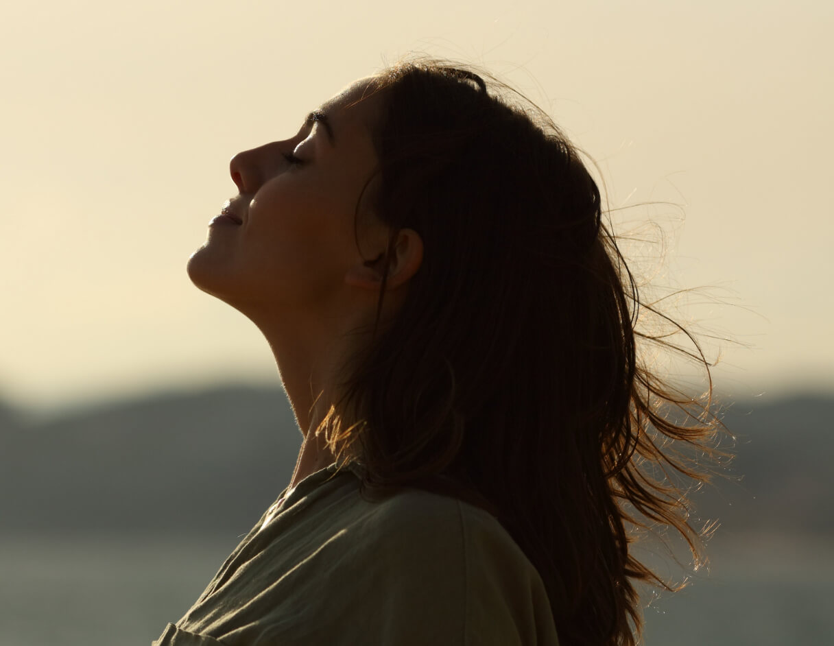 Woman feeling the wind while sun is setting
